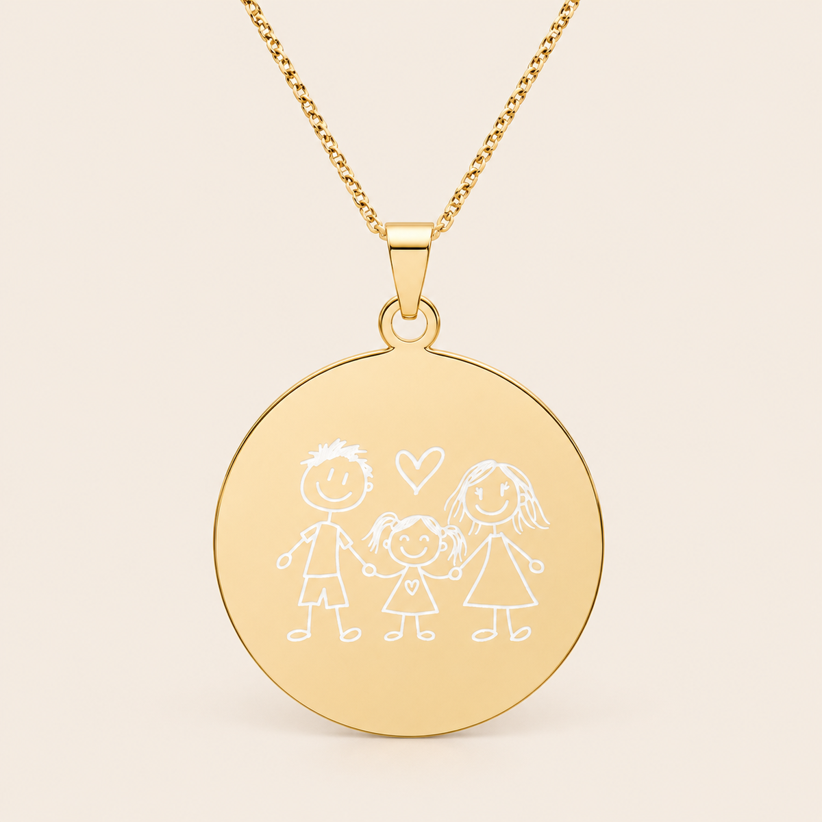 A gold round pendant necklace featuring a white engraved family illustration of three children and a heart, suspended from a gold chain against a light beige background.