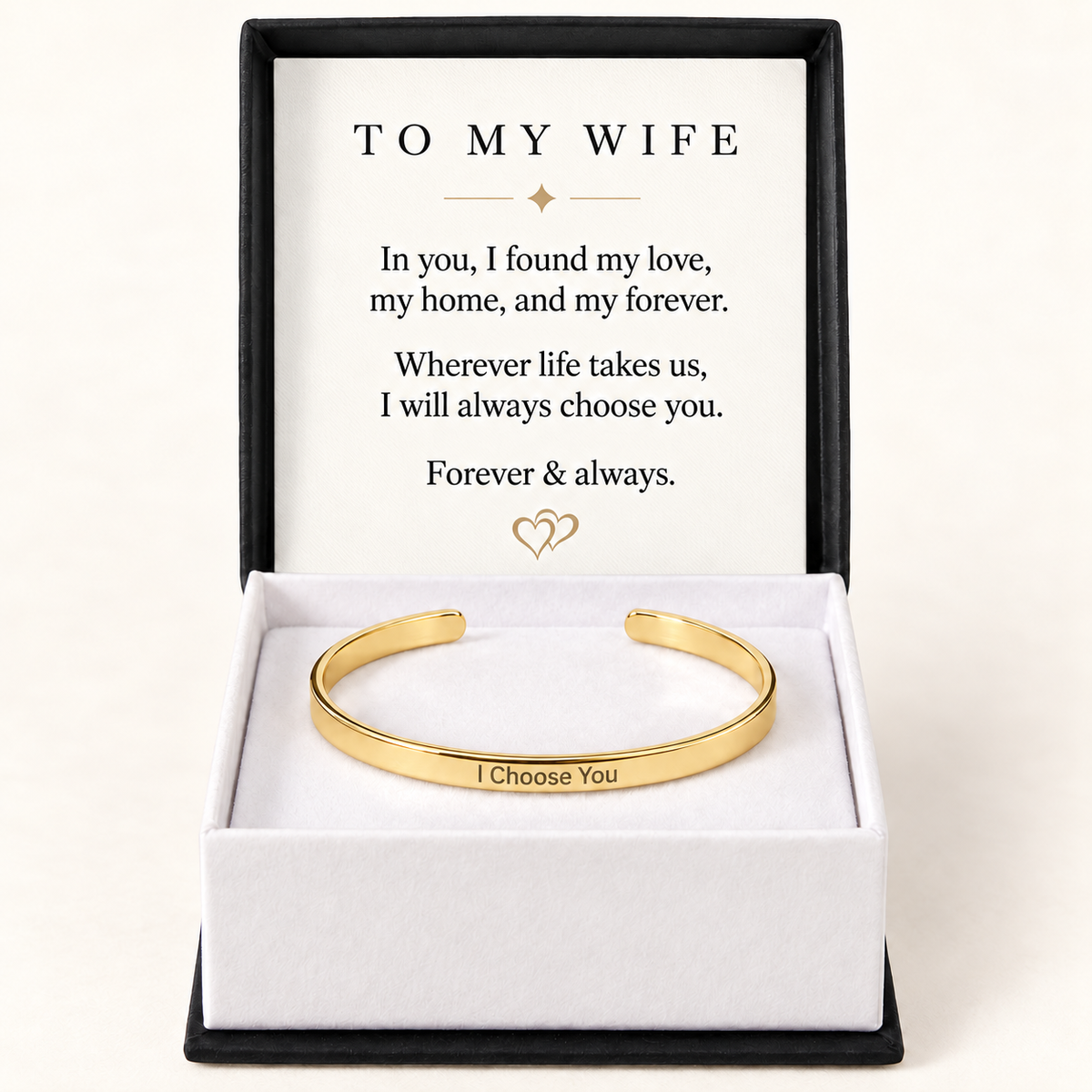 A gold open cuff bracelet engraved with 'I Choose You' presented in a white box with a black outer border. The inner lid features a printed message addressed 'TO MY WIFE'.