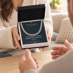 Wife giving her husband a silver Cuban link chain in a gift box